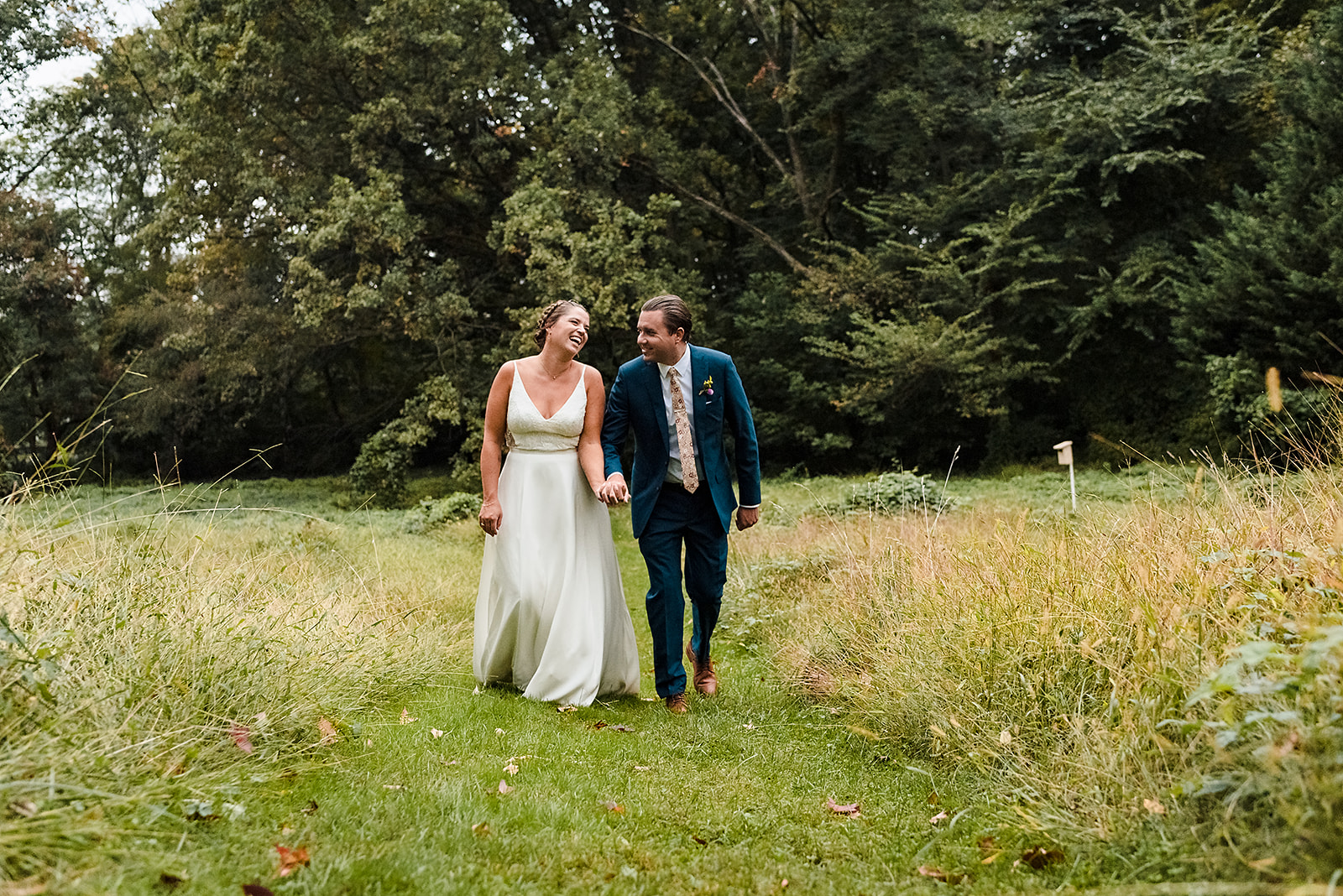 Walking bride and groom portrait in green gardens of Awbury Arboretum