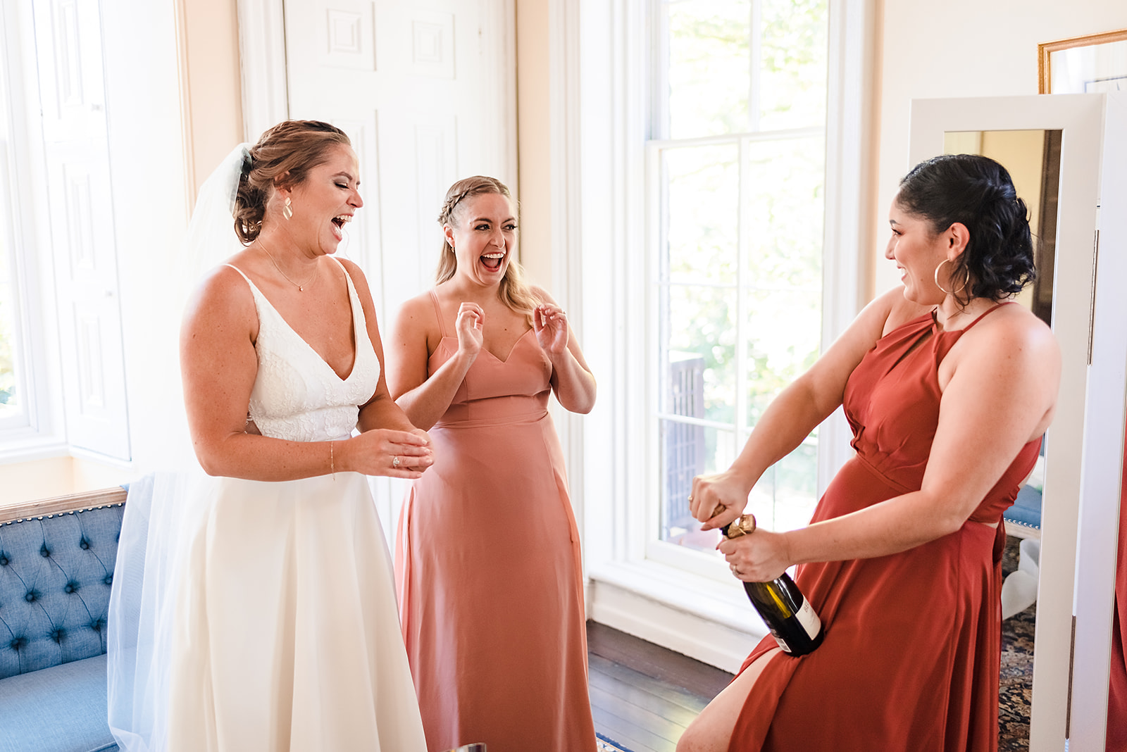 Bridesmaids and bride popping a champagne bottle