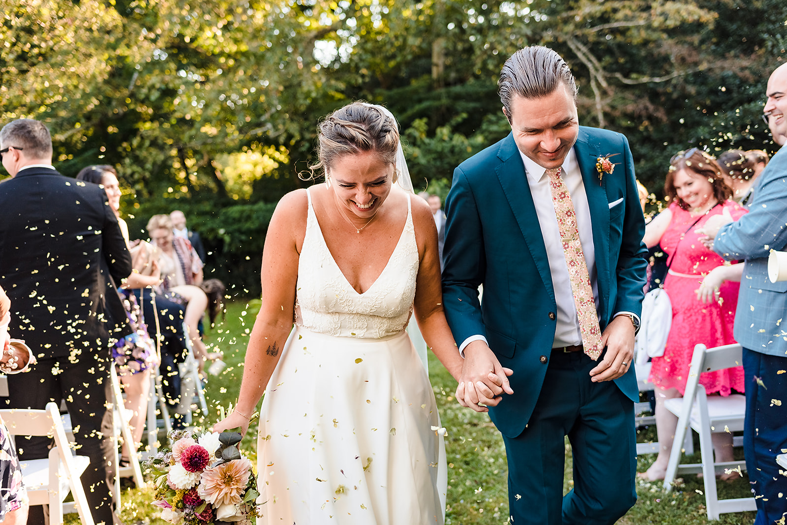 Bride and groom exiting Awbury Arboretum wedding ceremony under shower of eco-friendly dried flower confetti