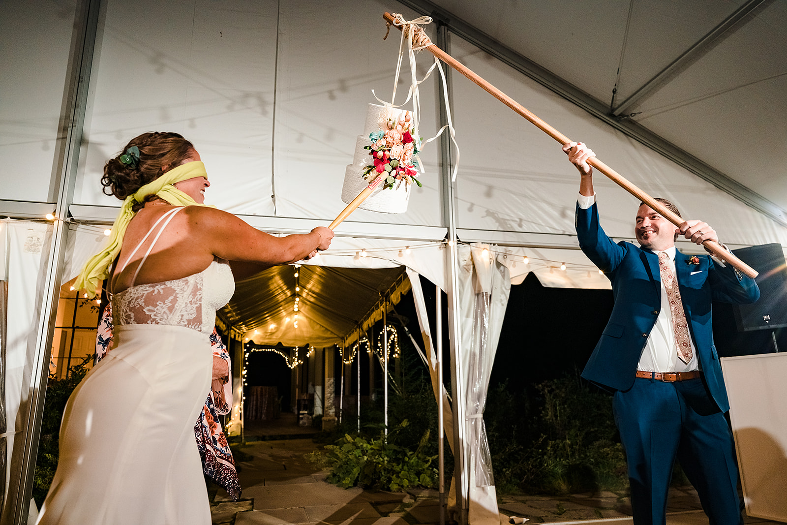 Bride swings at cake shaped piñata during wedding reception