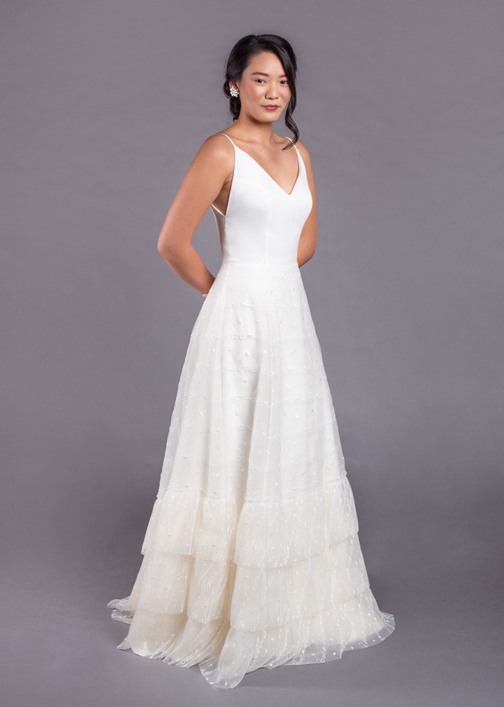 Bobbie is V neck silk crepe wedding gown with a tiered tulle skirt embroidered with hearts and the word love.