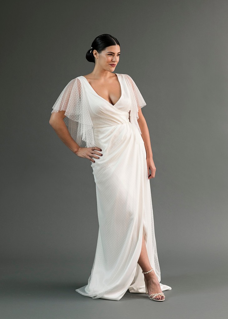 Lily is a charmeuse and swiss dot wedding dress with flutter sleeves and an illusion back in a faux wrap silhouette.
