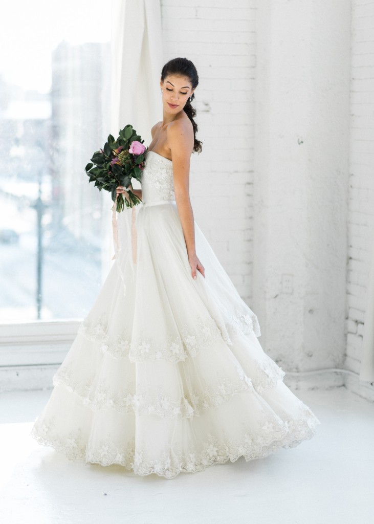 Penelope is a strapless modern ballgown wedding dress with 3D flower accents on the sweetheart neckline and tiered tulle skirt.