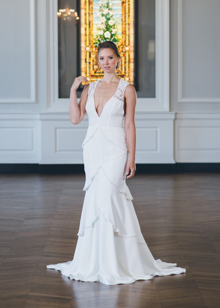 Zafirah by Edith Elan is a silk crepe wedding gown with a V neck lace bodice and tiered fit and flare skirt.