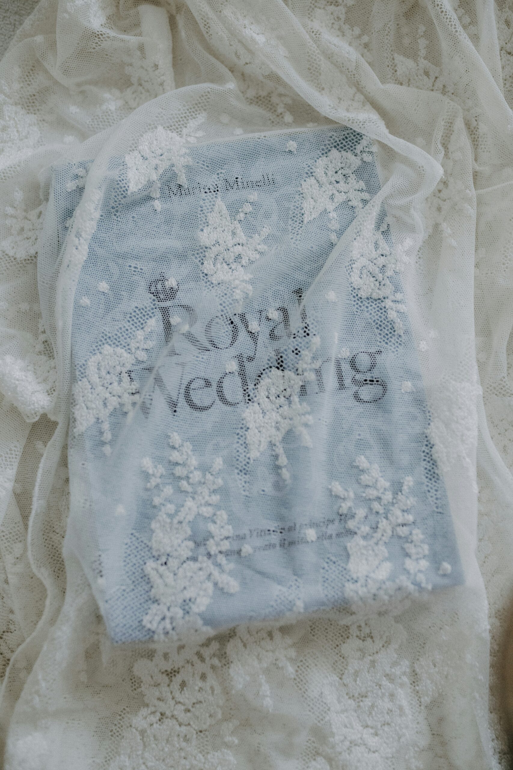 Blue book with black font called Royal Wedding sitting under a sheer lace fabric.