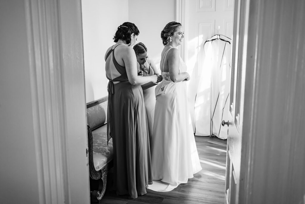 An Edith Élan bride getting into her custom convertible wedding dress with the help of her bridesmaids.