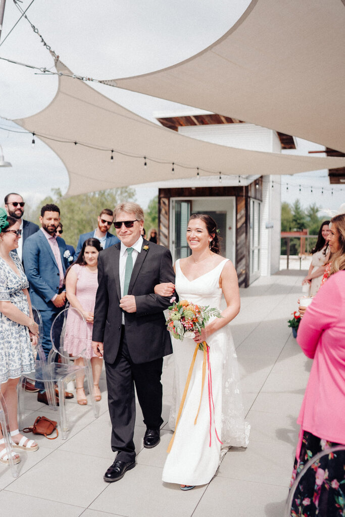 The bride and father of the bride walking down the aisle at the Highland Brewing rooftop