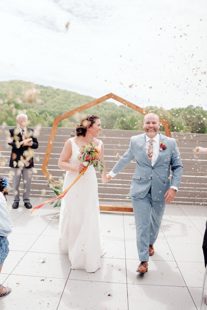 Bride and groom exiting the wedding ceremony under a shower of dried flower petals