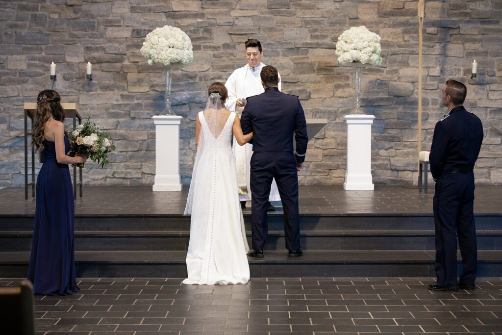 Groom in his Air Force uniform and bride in her bespoke wedding gown by Edith Élan at the altar