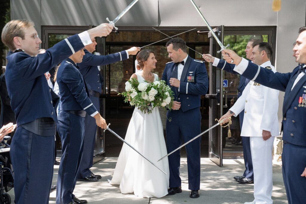 The bride and groom standing under the military sword arch after their wedding ceremony