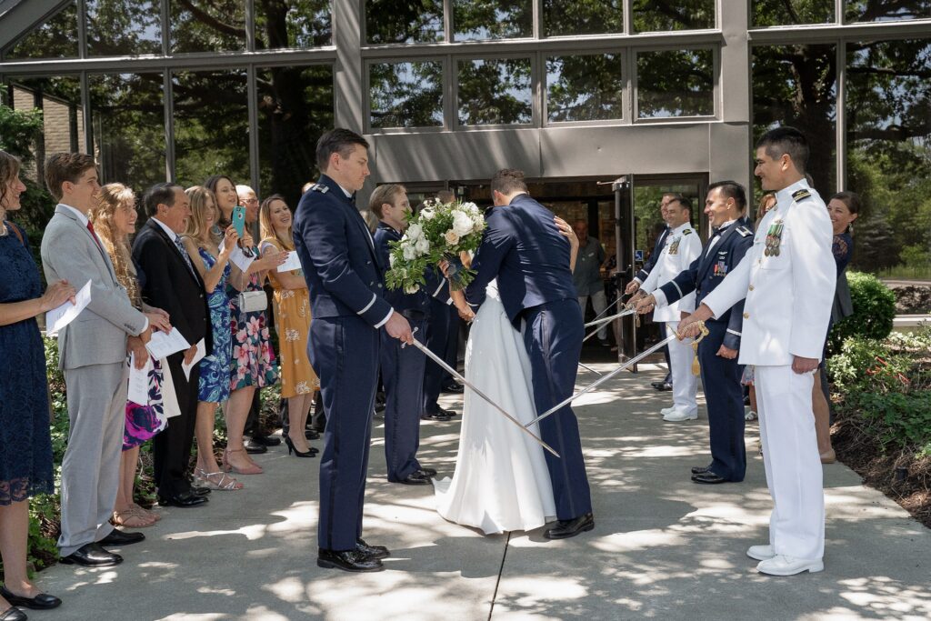Bride and groom kissing before exiting the military sword arch after their wedding ceremony
