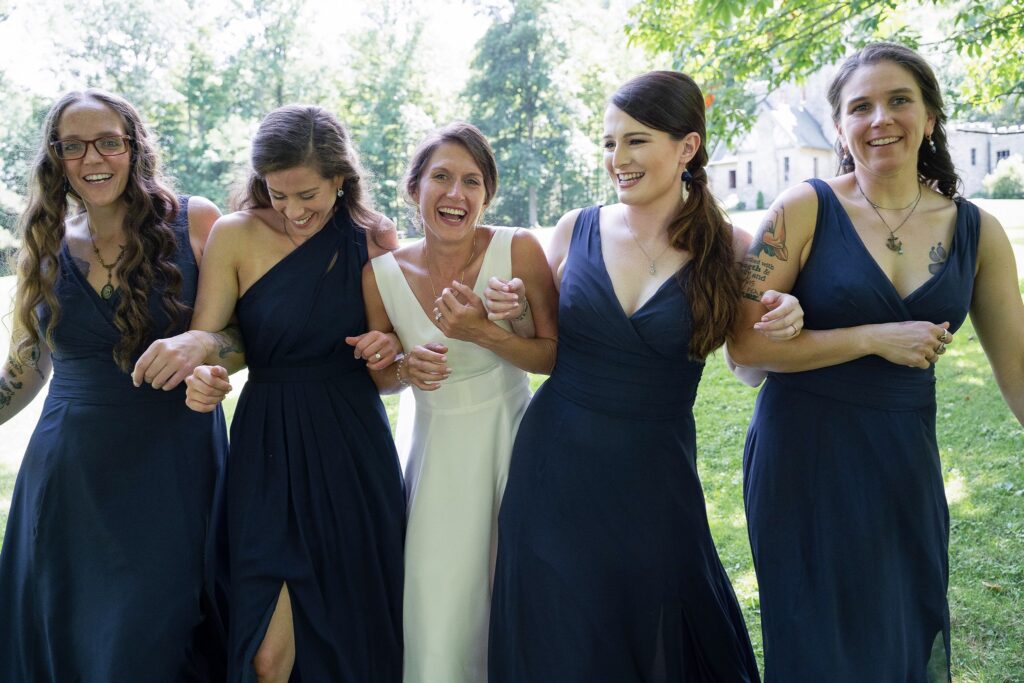 Bride in her bespoke wedding gown with her bridesmaids in navy blue dresses