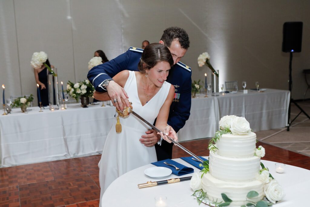 Bride and groom cutting their wedding cake with a military sword