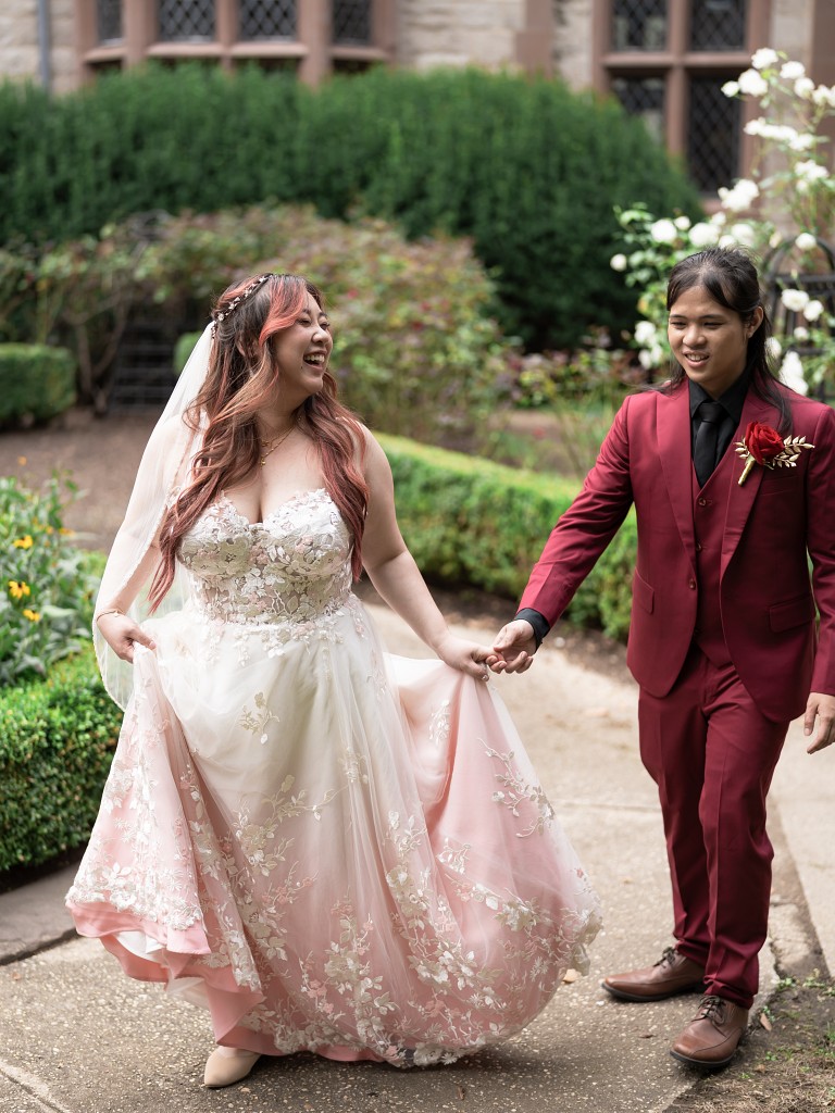 Bride wearing a custom blush and lace wedding dress with her groom wearing a red and black suit.