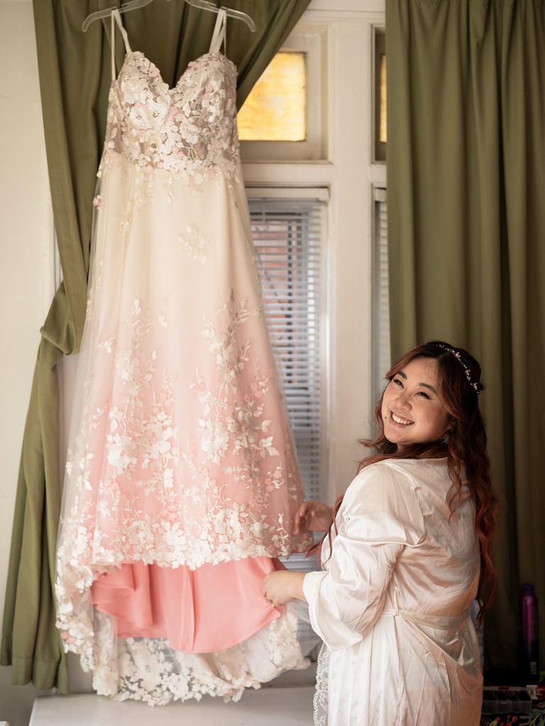 NYC bride next to her custom blush and lace wedding dress by designer Edith Élan before the ceremony.
