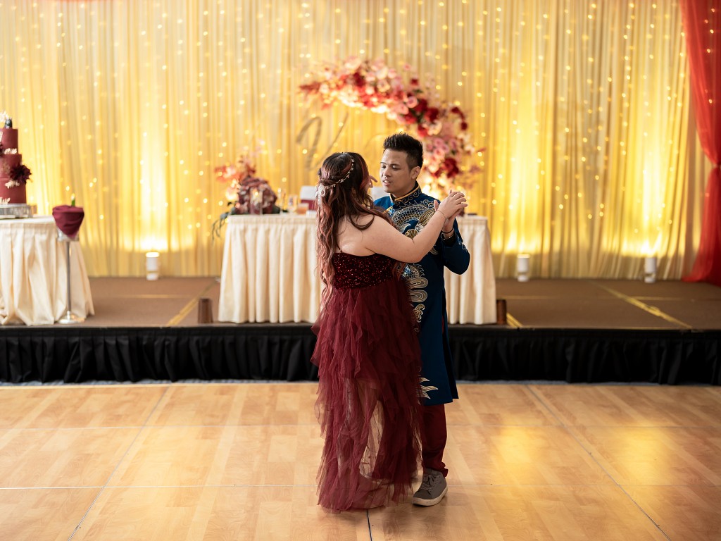 Bride in a red dress and groom in a traditional blue Vietnamese Ao Dai during their first dance.