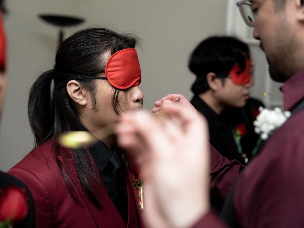 Blindfolded groom playing the Four Flavors of Life Chinese wedding door game.