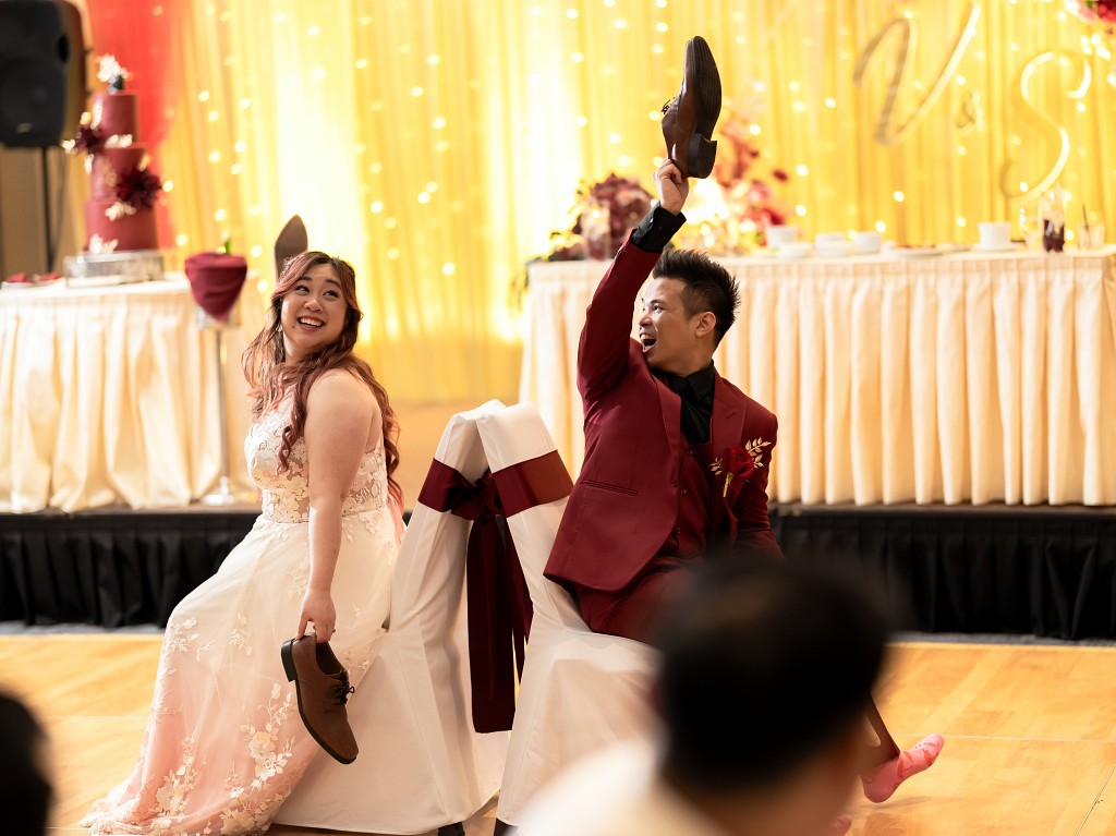 Bride in custom blush and lace wedding dress playing a newlywed game at the reception. NYC wedding.